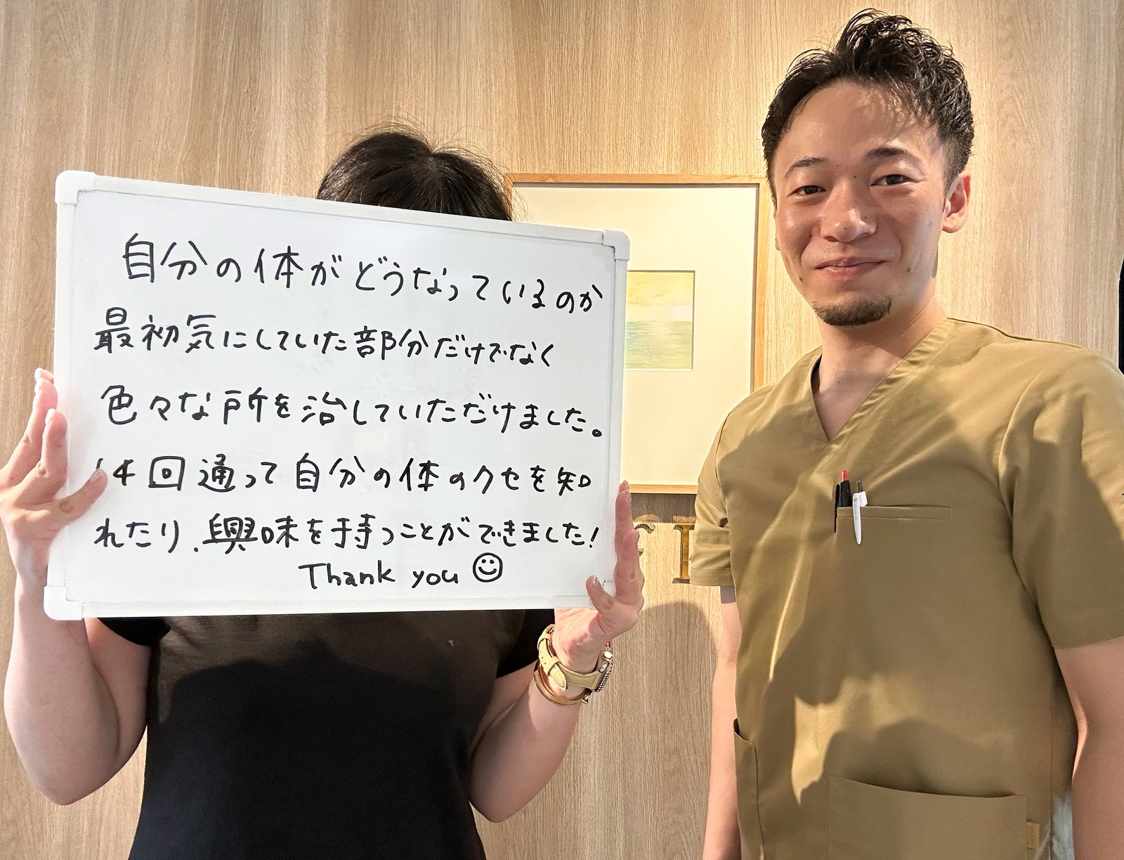 メッセージを書いたホワイトボードを持つ患者さまと院長