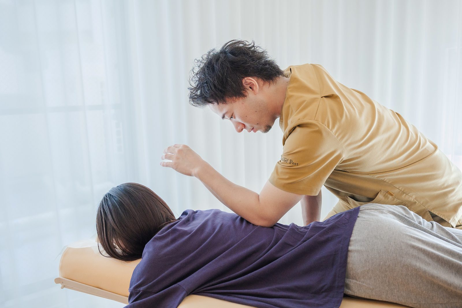 呼吸に合わせて、背中や肋骨まわりに手技を行っている様子