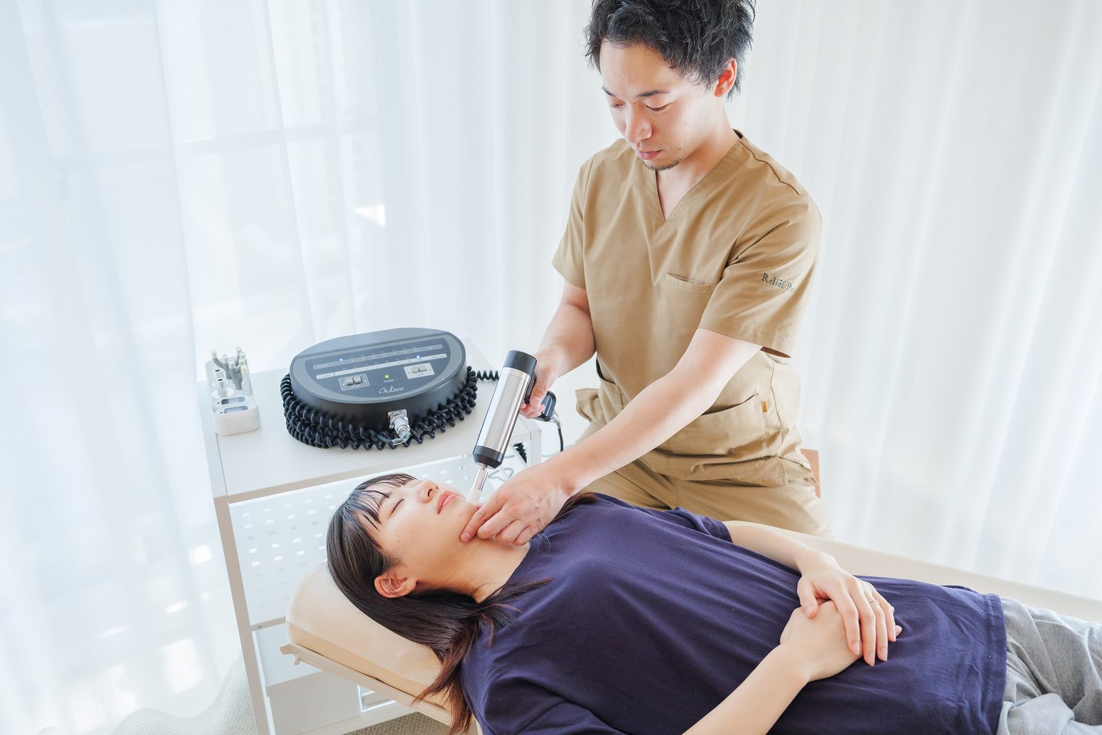 施術ベッドで、顔まわりに振動刺激を加えている施術の様子